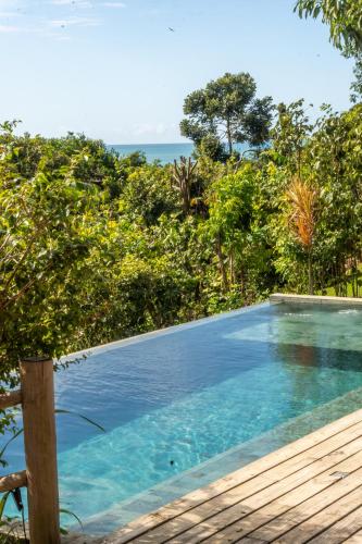 a swimming pool with a view of the ocean at Hotel Boutique Bahia Bonita in Trancoso