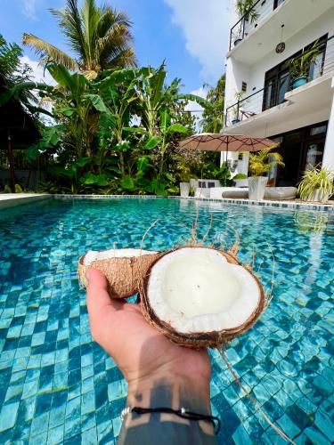 a person holding a coconut in front of a swimming pool at The Jini House in Ahangama