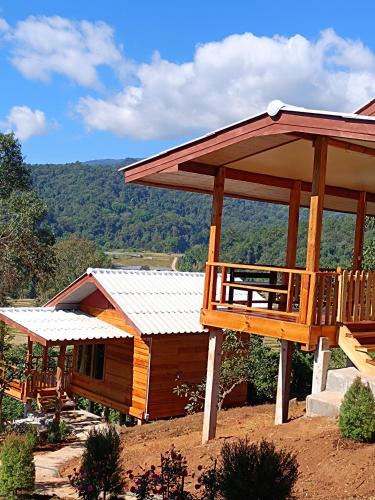a large wooden cabin with a large deck on a hill at อินทนนท์สุขุมทิพย์ โฮมสเตย์ in Ban Yang