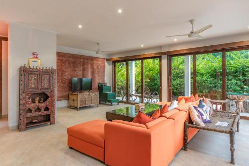 een woonkamer met een oranje bank en een televisie bij Villa Lakshmi in Temukus