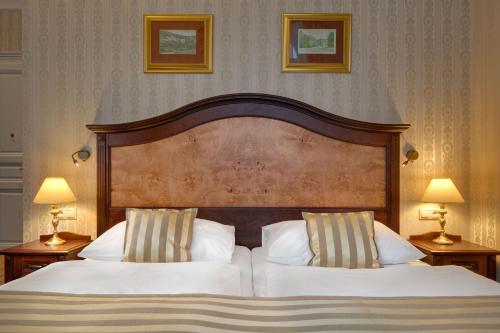 a bedroom with a bed with two pillows and two lamps at Ensana Nové Lázně in Mariánské Lázně
