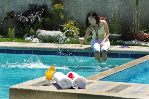 a woman sitting in the water next to a swimming pool at Hanan Hotel Tagaytay - Formerly Tagaytay Wingate Manor in Tagaytay