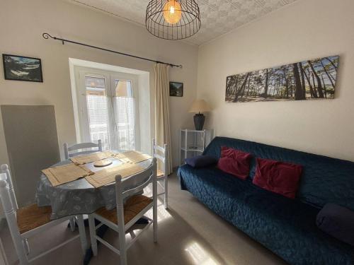 un salon avec un canapé bleu et une table dans l'établissement Charmant T2 Cabine au centre de Cauterets, parking et local à ski - FR-1-812-91, à Cauterets