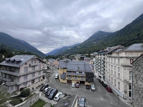 une ville avec des voitures garées dans un parking avec des montagnes dans l'établissement Studio cosy en centre-ville avec balcon et cellier à skis - FR-1-812-15, à Cauterets
