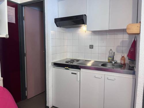 une petite cuisine avec des armoires blanches et un évier dans l'établissement Studio centre-ville proche télécabines, accès skis - FR-1-812-28, à Cauterets