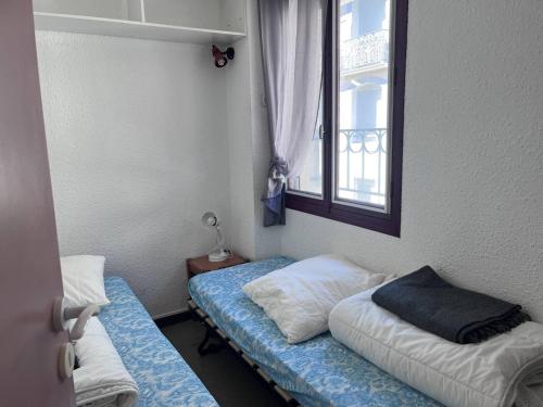 une chambre avec deux lits et une fenêtre dans l'établissement Studio centre-ville proche télécabines, accès skis - FR-1-812-28, à Cauterets
