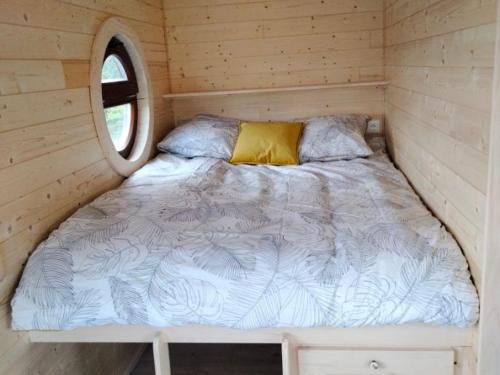 - un lit dans une petite maison avec fenêtre dans l'établissement Séjour pittoresque en roulotte équipée - FR-1-410-455, à Cérans-Foulletourte