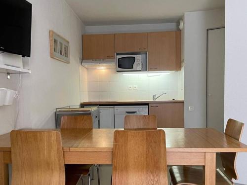 une cuisine avec une table et des chaises et un micro-ondes dans l'établissement Appartement familial à Cauterets, proche centre - FR-1-812-32, à Cauterets