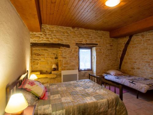 Charmante maison rustique en pierres, proche de Sarlat - FR-1-616-385 في Marcillac-Saint-Quentin: غرفة نوم بسريرين في مبنى حجري