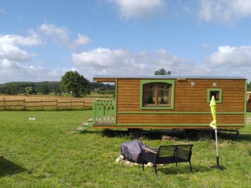 une petite maison dans un champ avec un banc dans l'établissement Séjour pittoresque en roulotte équipée - FR-1-410-455, à Cérans-Foulletourte