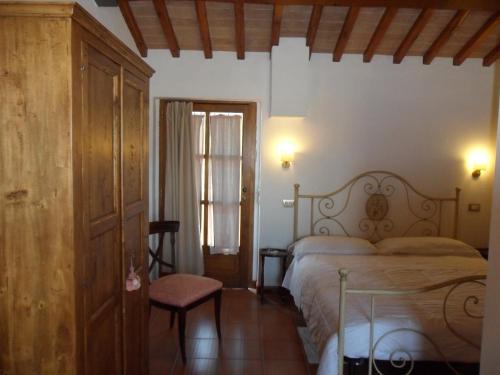 a bedroom with a bed and a chair and a window at Fullino Nero Rta - Residenza Turistico Alberghiera in Siena