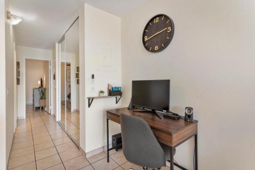 a desk with a television and a clock on a wall at Cute Ocean View Condo, walk to beach LSV03 in Kihei