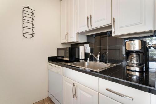 a kitchen with white cabinets and a sink at Cute Ocean View Condo, walk to beach LSV03 in Kihei