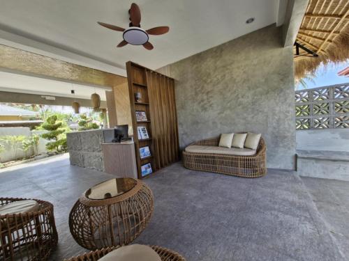 a living room with a ceiling fan and wicker chairs at Villa Alessandra Homestay in Moalboal