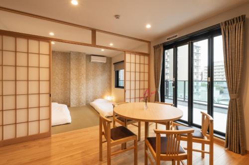 a room with a table and chairs and a bedroom at TEN APARTMENT HOTEL Hakata Reisen in Fukuoka