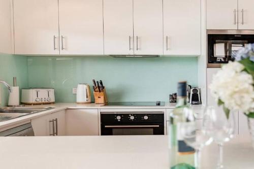 a kitchen with white cabinets and a table with a vase of flowers at Tranquility with Spa & Jetty in Woy Woy