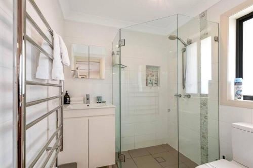 a bathroom with a glass shower and a sink at Tranquility with Spa & Jetty in Woy Woy