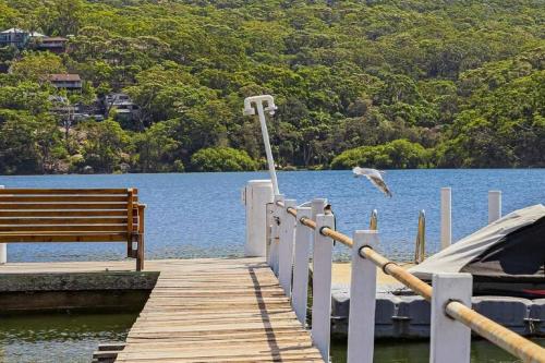 a bird flying over a dock next to a bench at Tranquility with Spa & Jetty in Woy Woy