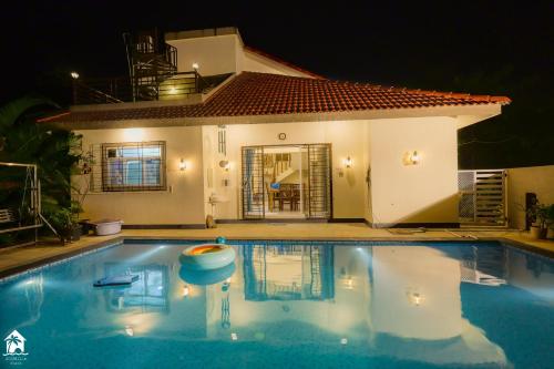 a swimming pool in front of a house at night at Parambi by Soumils Stays in Longhar