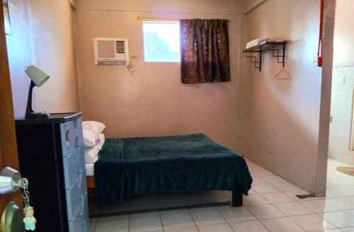 Una pequeña habitación con una cama y una ventana. en TheLavanderDream of Terbaik Apartments, en Puerto Princesa City