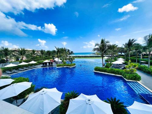 a pool at a resort with white umbrellas at Hese Pool Villas & Resort Cam Ranh in Cam Ranh