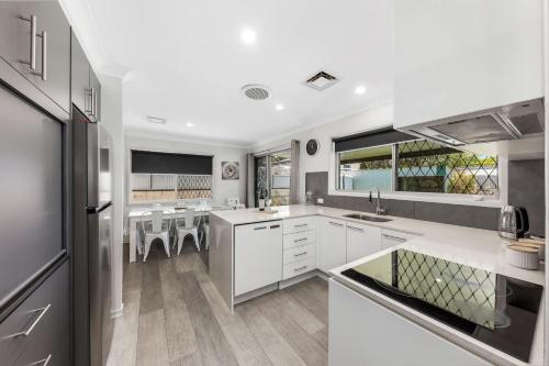 a large kitchen with white cabinets and a dining area at Pet Friendly home in Maroochydore in Maroochydore
