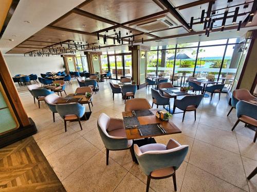 a dining room with tables and chairs and windows at Hese Pool Villas & Resort Cam Ranh in Cam Ranh