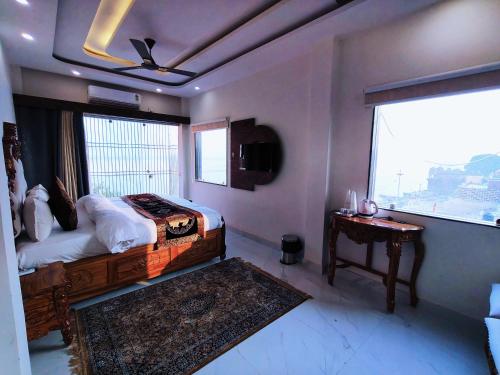 a bedroom with a bed and a window and a table at Hotel Shannti Inn in Varanasi