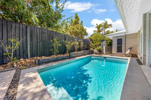 a swimming pool in a backyard with a fence at Pet friendly Holiday home with pool on Alex in Alexandra Headland