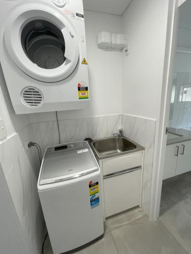 a small kitchen with a washing machine and a sink at The Noosa Apartments in Noosa Heads