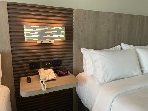 a hotel room with a bed and a telephone at Holiday Inn Express Mérida by IHG in Mérida