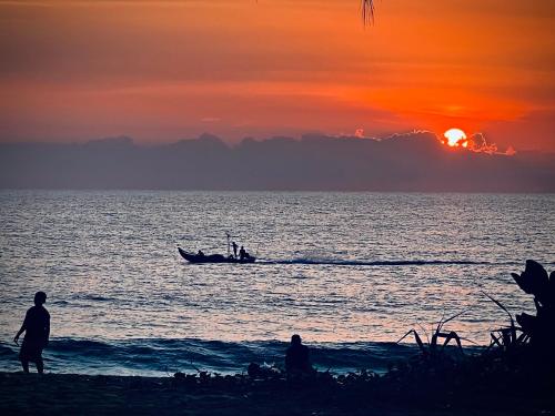 two people standing on the beach with a boat in the ocean at Turtle Tales-Mafueang,Turtle Beach,Phang-Nga in Phang-nga