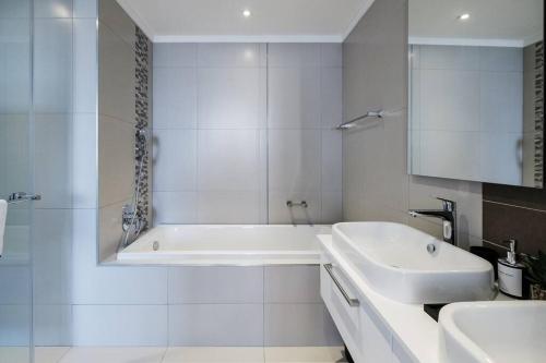a white bathroom with a tub and a sink at Masingita Towers - Luxurious Apartment Condo in Sandton in Johannesburg