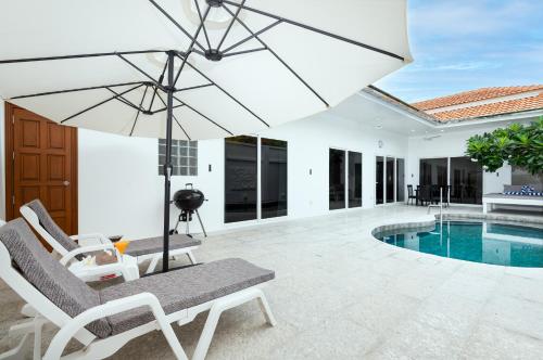 a patio with a chair and an umbrella and a pool at Villa Franken Luxury Pool Villa in Pattaya South