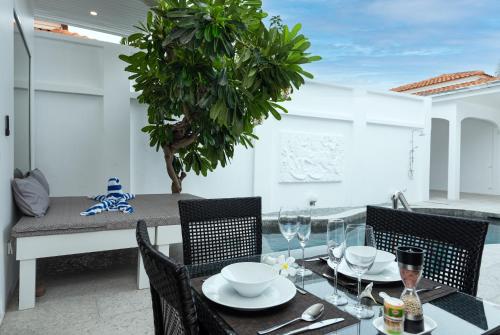 a dining table and chairs with a table and a tree at Villa Franken Luxury Pool Villa in Pattaya South