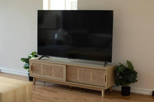 a flat screen tv on a stand in a living room at Central Delight in Dubbo