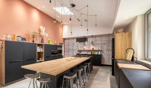 une cuisine avec un grand îlot en bois et des tabourets de bar dans l'établissement Maison de charme - 15 min de Lyon, à Saint-Romain-au-Mont-dʼOr