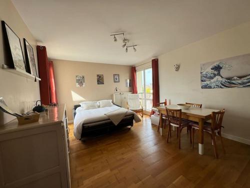 a bedroom with a bed and a table and a dining room at Appartement résidence calme proche centre-ville in Caen