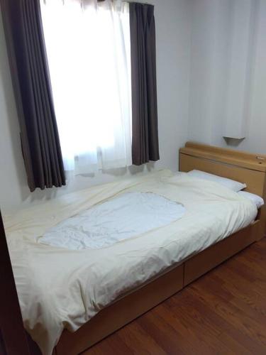 a bed in a room with a window at メゾンジョイ久須志#101 in Asahimachi