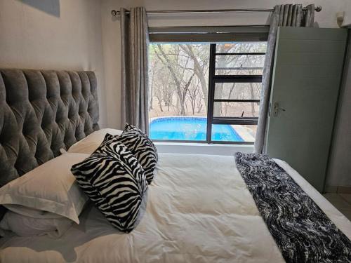 a bedroom with a bed with zebra pillows and a window at Kruger Amani Bush Retreat in Marloth Park