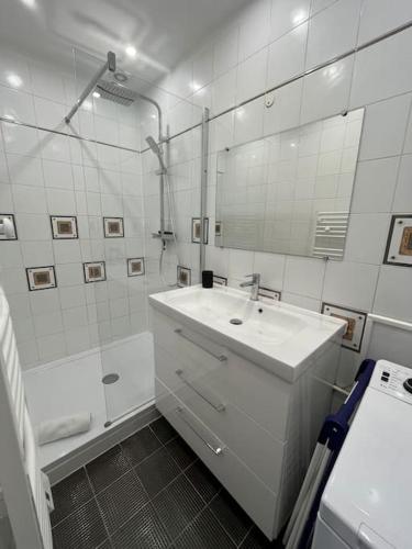 une salle de bain blanche avec un lavabo et une douche dans l'établissement Bel appartement Hyper-centre, à Caen