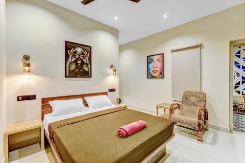 a bedroom with a large bed and a chair at IZI Beach Stay Mahabalipuram in Chennai