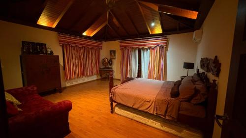 a bedroom with a bed and a couch in it at Laman Padi Villa in langkawi in Ulu Melaka