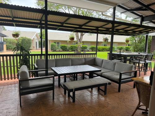a patio with a couch and tables and chairs at Mareeba Motor Inn in Mareeba