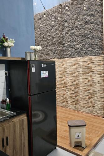 a black refrigerator in a kitchen with a wall at DYAZA LV Pekanbaru Near Sultan Syarif Kasim Airport and UIR in Pekanbaru