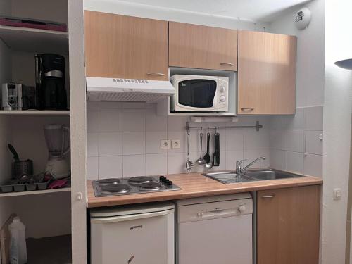 une petite cuisine avec un évier et un micro-ondes dans l'établissement Appartement cosy Cauterets près des télécabines - FR-1-812-38, à Cauterets