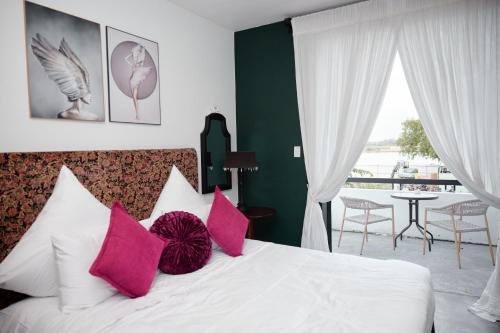 a bedroom with a white bed with pink pillows at Thao Dien Village Boutique Hotel in Ho Chi Minh City