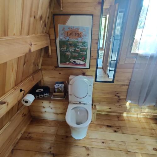 a bathroom with a toilet in a wooden room at Tipi Cheyenne des monteaux in Vivy