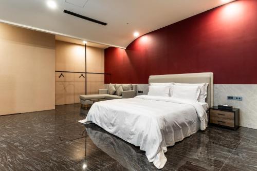 a bedroom with a white bed and a red wall at OHYA Chain Boutique Motel Taoyuan in Taoyuan