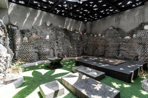 a room with a stone wall with a table and benches at OHYA Chain Boutique Motel Taoyuan in Taoyuan